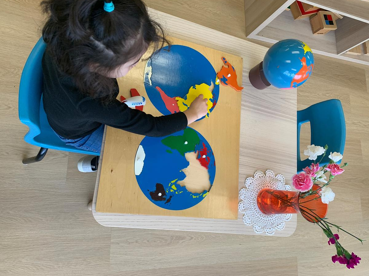 Elementary student working with the Montessori world puzzle map at IMA